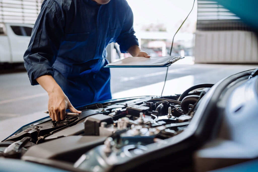 Mechaniker inspiziert die Motorhaube eines Autos